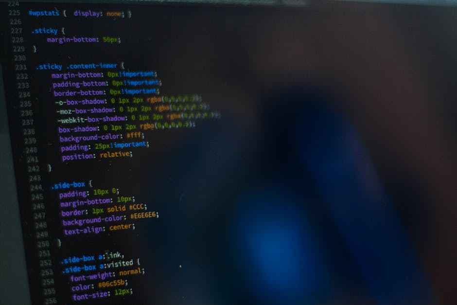 A digital screen displaying lines of colored code in a programming language, with syntax highlighting in shades of green, yellow, purple, and blue against a dark background. The code includes CSS styl